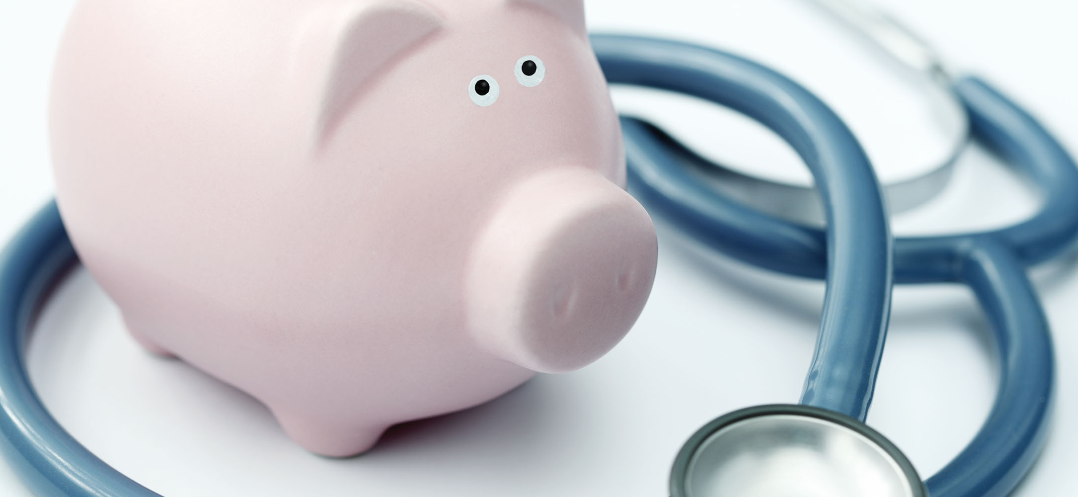 Pink piggy bank surrounded by a stethoscope